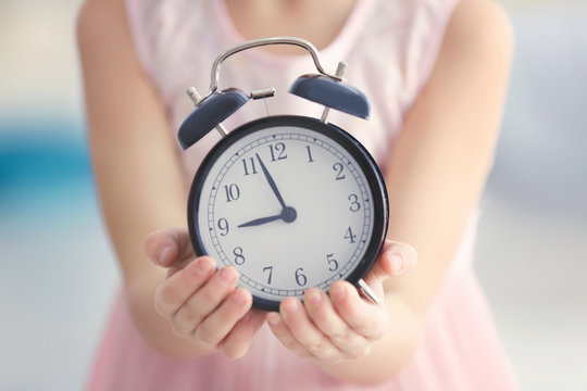 Cute little girl with alarm clock, closeup