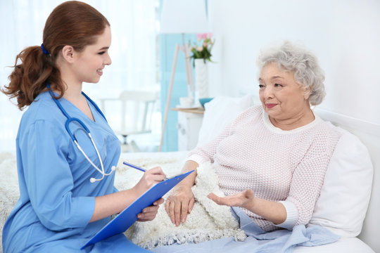 Nurse talking with elderly woman in light room