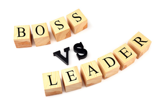 Wooden cubes and black letters forming text BOSS VS LEADER isolated on white