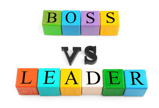 Lines of colorful wooden cubes and black letters forming text BOSS VS LEADER isolated on white