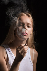 blond young woman smoking joint on black background