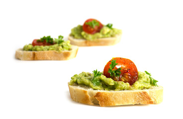 canapes with avocado cream or guacamole and tomatoes isolated on a white background, healthy party sandwiches, closeup