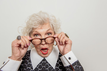 Surprised senior lady adjusting her glasses