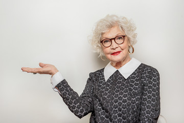Joyful senior lady showing something by her arm