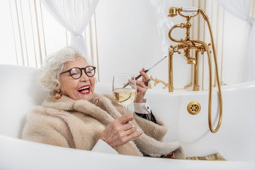 Joyful mature lady relaxing in bathtub