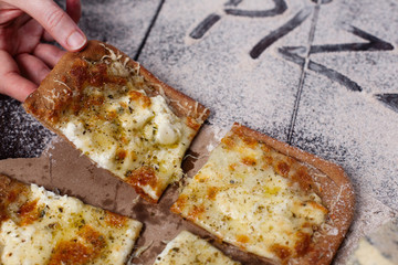 The female hand takes a slice of pizza four cheese with oregano and olive oil. quattro fromaggi