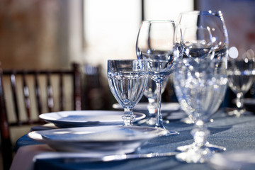 Wedding. Banquet. The chairs and round table for guests, served with cutlery and crockery and covered with a blue tablecloth.