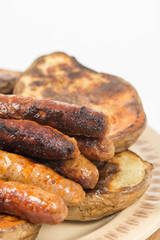 Baked potatoes with grilled bbq sausages on the plate