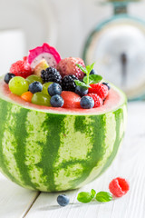 Delicious fruits salad in watermelon in sunny kitchen
