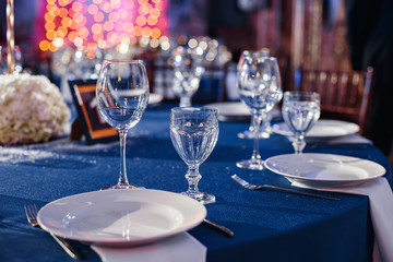 Wedding. Banquet. The chairs and round table for guests, served with cutlery and crockery and covered with a blue tablecloth.