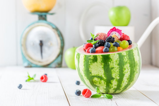 Exotic fruits salad in watermelon in sunny kitchen