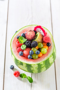 Tasty fruits salad in watermelon in sunny kitchen