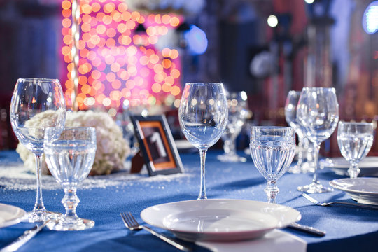 Wedding. Banquet. The chairs and table for guests, served with cutlery and crockery and covered with a blue tablecloth.