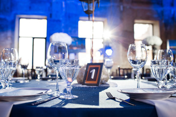 Wedding. Banquet. The chairs and round table for guests, served with cutlery and crockery and covered with a blue tablecloth.