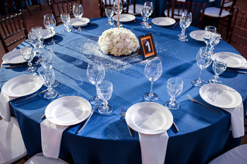Wedding. Banquet. The chairs and round table for guests, served with cutlery and crockery and covered with a blue tablecloth.