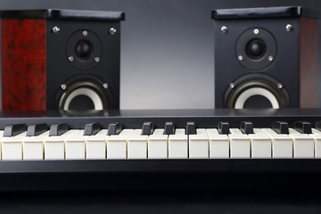 two stereo audio speakers and piano keys closeup on dark background