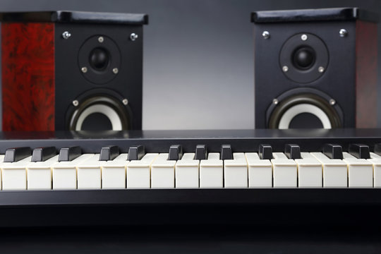 two stereo audio speakers and piano keys closeup on dark background