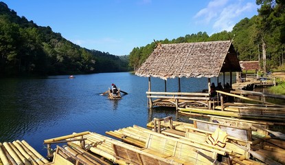 Tourists sitting on the bamboo rafts floating in Pang Oung Lake (Pang Tong reservoir) during golden sunrise morning , Mae hong son, Thailand.