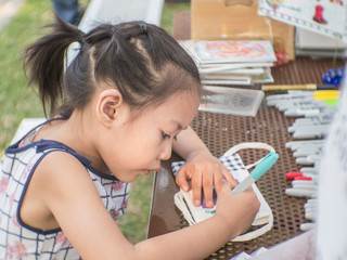 Cute Asian child drawing in a park.