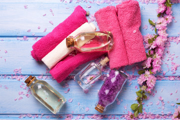 Bottles with spa products, flowers and towels   on  blue wooden background.