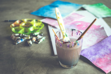 watercolor art table paints, art brushes, glass of water.