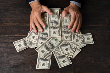 Man hands sweeping money,business concept.Lucky man winning  lots of us dollar from gambling,with smiling face and black background.