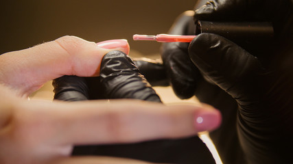 Macro view of nail polishing - female get professional manicure in beauty salon