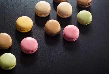 Colorful assorted french macaroons on a dark background.