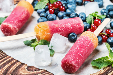 popsicles with berries and fruit on a wooden table. focus foreground