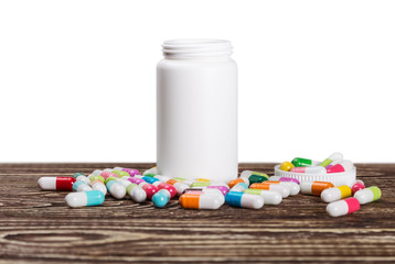 pills of different colors and a bottle of medicine on a white background isolated