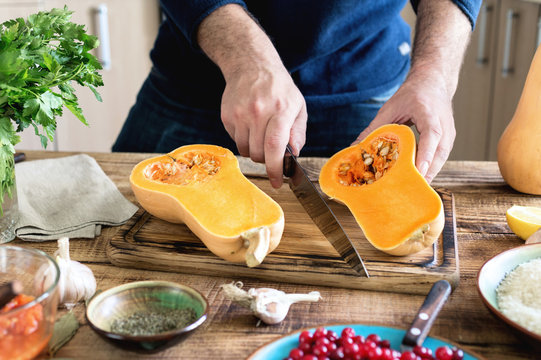 Man cooking butternut squash on wooden table in the kitchen
