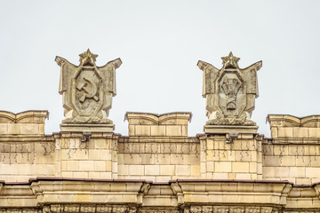 Fragment of parapet administrative government building with USSR symbols . Posters with the hammer and sickle, spikelets bunch. Ornament of the Stalinist Empire style of architecture.