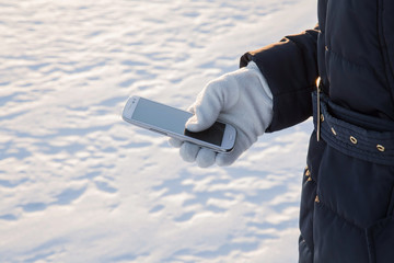 Woman wearing gloves using a mobile phone and try to find a way in snowy winter day.