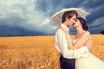 In love bride and groom in wheat field with blue sky in the background