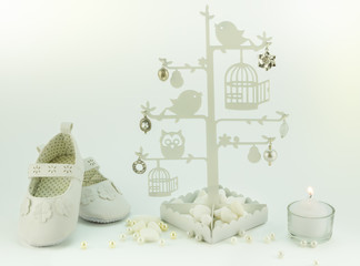 Baby white invitation birthday or christening background with booties, candle and charm tree