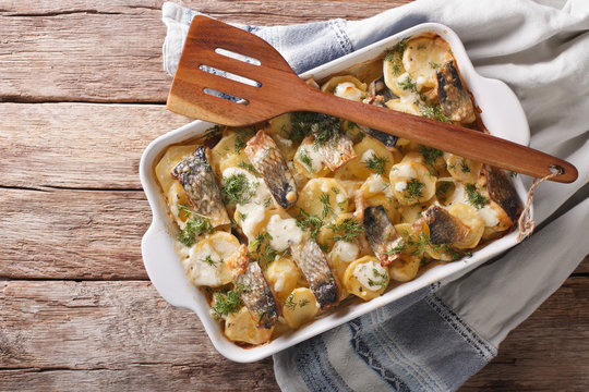 Finnish Food: Casserole with potatoes and herring close up in baking dish. horizontal top view