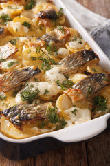 Finnish Food: Casserole with potatoes and herring close up in baking dish. Vertical