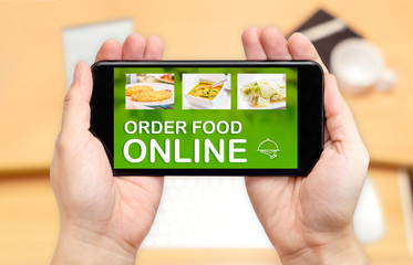 Watching two hand holding mobile phone with order food online word on screen and blur desk office background,Digital restaurant concept