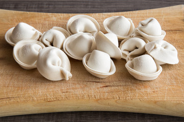 Frozen homemade dumplings on the wooden board in the kitchen. Healthy eating and lifestyle.