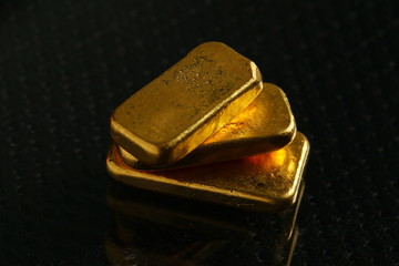 The gold bars put on the dark and gross surface background  represent the business and finance concept related idea. 