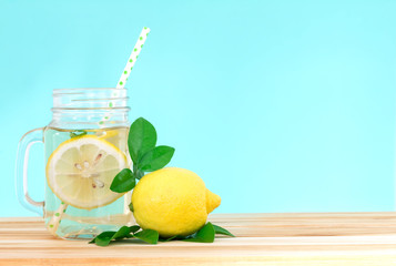  Citrus lemonade water with lemon sliced , healthy and detox water drink in summer on wooden table with blue lighten background