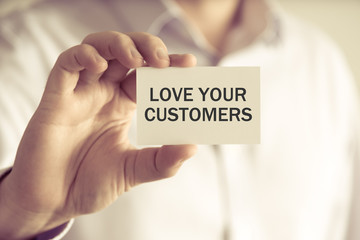 Businessman holding LOVE YOUR CUSTOMERS message card
