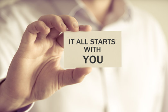 Businessman holding IT ALL STARTS WITH YOU message card
