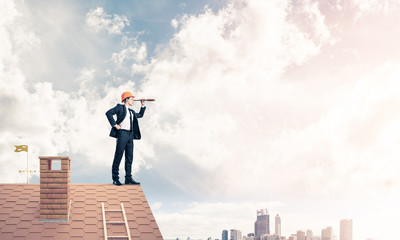 Engineer man standing on roof and looking in spyglass. Mixed med