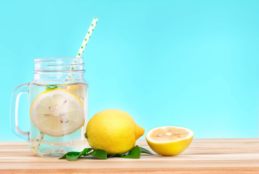  Citrus lemonade water with lemon sliced , healthy and detox water drink in summer on wooden table with blue lighten background