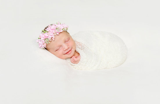 newborn baby swaddled in white diaper smiling asleep