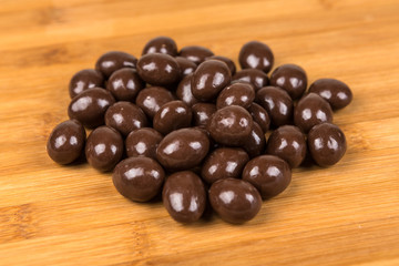 Milk chocolate almonds isolated on a wood background