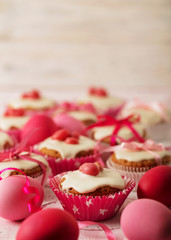 Easter cupcakes with white icing decorated with pink candy and ribbons.