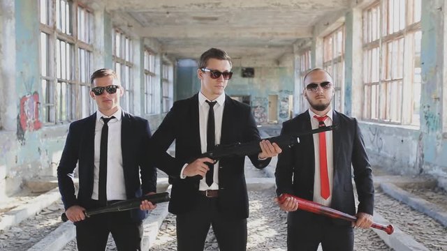 three mens with weapons in abandoned building