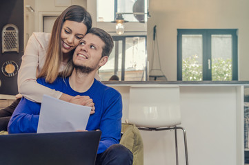 Young people studying from home with laptop computer, Affectionate woman looking at her boyfriend working on the laptop at home